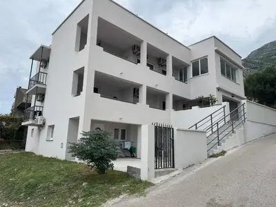 a white building with a gate in front of it at Sutomore Apartman in Sutomore