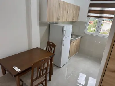a small kitchen with a table and a refrigerator at Sutomore Apartman in Sutomore