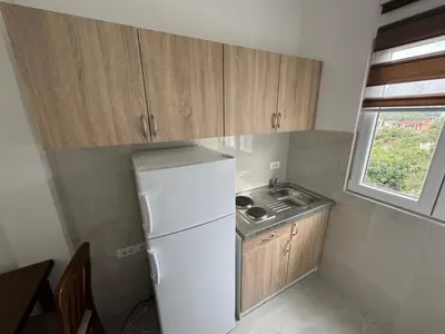 a small kitchen with a white refrigerator and a window at Sutomore Apartman in Sutomore