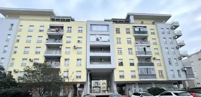 a tall yellow building with cars parked in front of it at Urban studio Blok 9 in Podgorica