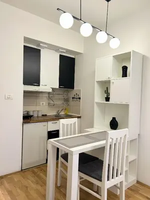 a kitchen with white cabinets and a table and chairs at Urban studio City kvart in Podgorica