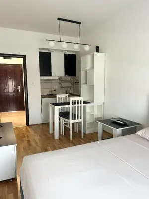 a bedroom with a bed and a table and a kitchen at Urban studio City kvart in Podgorica