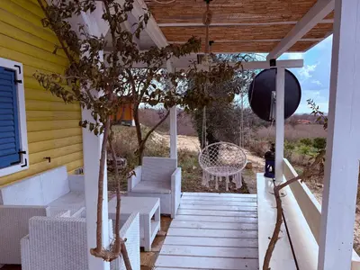 a porch with white furniture on a yellow house at La Belle Saison