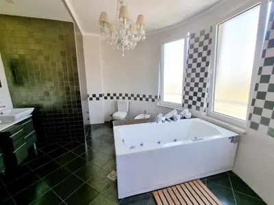 a bathroom with a tub and a sink and a chandelier at Le Domaine paradise