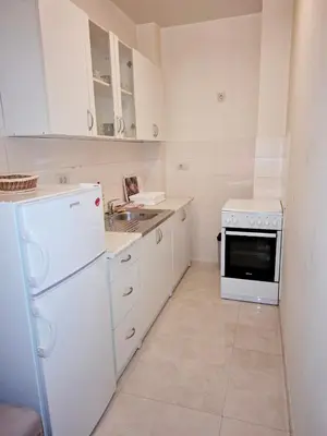 a white kitchen with a sink and a refrigerator at City kvart apartman in Podgorica