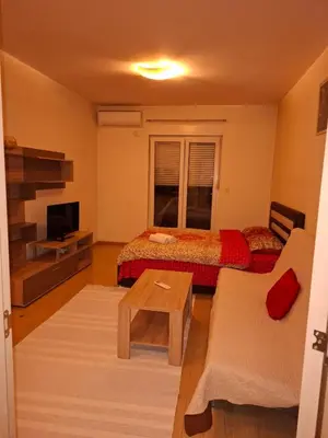 a living room with two beds and a tv at City kvart apartman in Podgorica