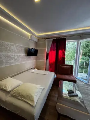 a bedroom with a bed and a chair and a window at Oaza mira Sutomore in Bar