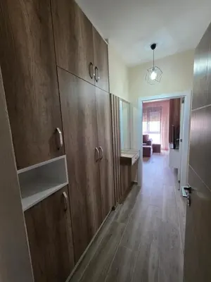 a kitchen with wooden cabinets and a hallway at S&M Stan in Ulcinj