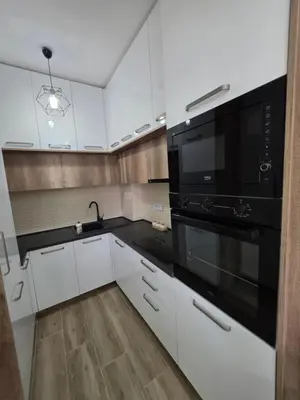a kitchen with white cabinets and a black microwave at S&M Stan in Ulcinj