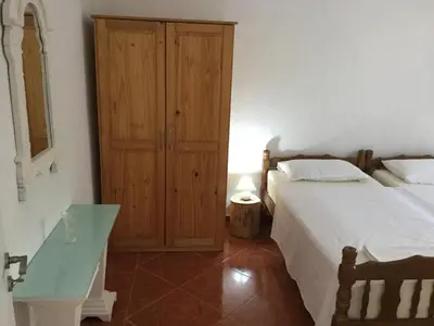a bedroom with two beds and a wooden cabinet at Apartment Dorada in Dobra Voda