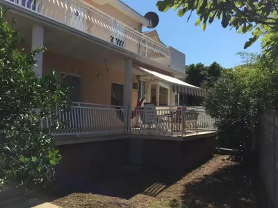 a house with a porch with a flag on it at Apartment Dorada in Dobra Voda