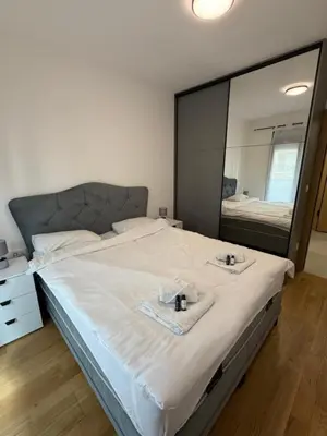 a bedroom with a large bed with two towels and a mirror at Montenegro Platinum Suite - New City in Podgorica