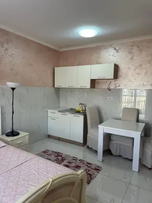 a kitchen with a white table and a table and chairs at Rose Stay Podgorica in Podgorica