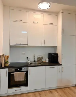 a kitchen with white cabinets and a sink at Azure Teuta apartment with balcony in Ulcinj