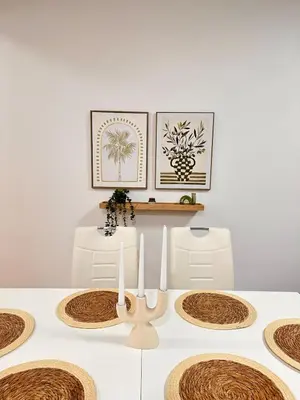 a dining room table with white chairs and framed pictures at Azure Teuta apartment with balcony in Ulcinj