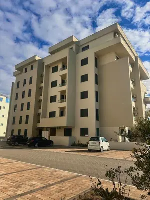 a large building with cars parked in a parking lot at Azure Teuta apartment with balcony in Ulcinj