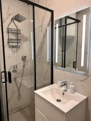 a white bathroom with a shower and a sink at Azure Teuta apartment with balcony in Ulcinj