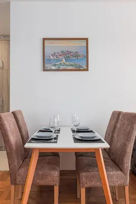 a dining room table with chairs and a picture on the wall at Panoramic Sea View 1BD Apartment in Becici