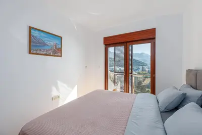 a bedroom with a bed and a large window at Panoramic Sea View 1BD Apartment in Becici