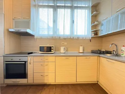 a kitchen with wooden cabinets and a microwave at MWA - City Soul Podgorica in Podgorica