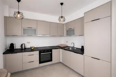 a kitchen with white cabinets and black counter tops at Bozovic Apartman 2 in Budva