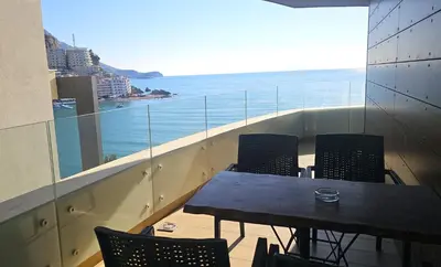 a table and chairs on a balcony with a view of the ocean at Azure Family Seaside Living Apartments Rafailovici in Becici