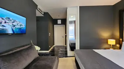 a bedroom with a bed and a tv on a wall at Azure Family Seaside Living Apartments Rafailovici in Becici