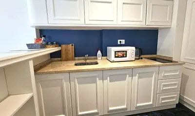 a kitchen with white cabinets and a microwave on a counter at Azure Family Seaside Living Apartments Rafailovici in Becici