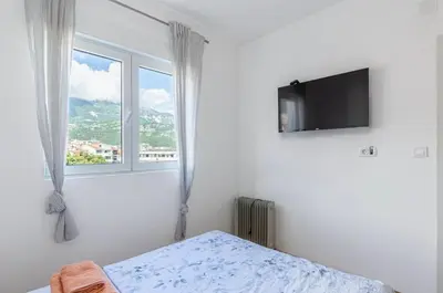 a white bedroom with a bed and a window at Evins Budva 1 Bedroom Apartment in Budva