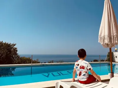 a young boy sitting on a chair next to a swimming pool at New ROZANA in Ulcinj