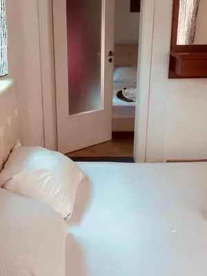 a bedroom with a white bed and a open door at New ROZANA in Ulcinj