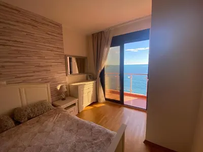a bedroom with a bed and a view of the ocean at Apartament Nadia DUBRAVA BAR in Dobra Voda