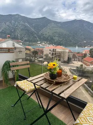 a wooden table with flowers on top of a balcony at Dobrota Luxury House with Kotor Gulf View in Dobrota