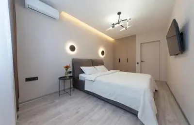 a bedroom with a large white bed and a television at Apartmani Drivasko in Sveti Stefan