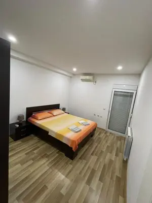 a bedroom with a bed and a wooden floor at Apart Sara in Ulcinj