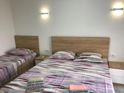 a bedroom with two beds and two lamps on the wall at Apart Sara in Ulcinj