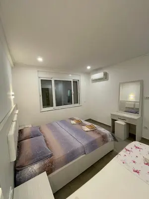 a bedroom with a large bed and two windows at Apart Sara in Ulcinj