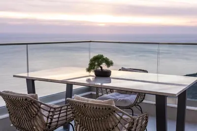 a table with chairs and a potted plant on a balcony at Seaview Residence in Dobra Voda