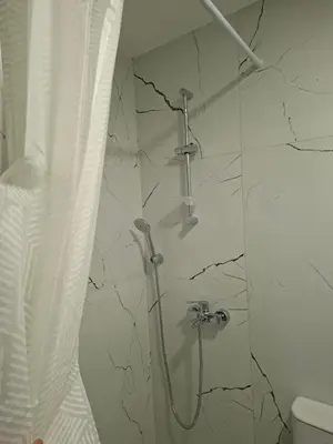 a shower in a bathroom with a marble wall at Apartman Asia in Podgorica