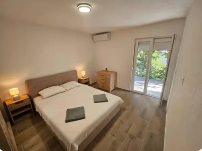 a bedroom with a large bed and a sliding glass door at Apartment Under the Palm Tree in Budva