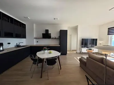 a kitchen and living room with a table and a couch at Exclusive penthouse with stunning panoramic views in Prijevor
