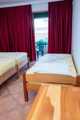 two beds in a room with red curtains at Beach House Noki 1 in Ulcinj