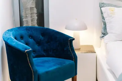 a blue chair in a bedroom next to a bed at Hotel Senator Lux in Ulcinj