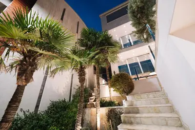 a building with palm trees in front of it at Hotel Senator Lux in Ulcinj