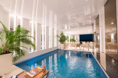 a swimming pool in a building with chairs and a table at Hotel Senator Lux in Ulcinj