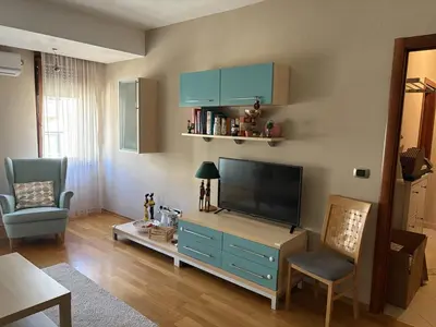 a living room with a flat screen tv and a blue cabinet at Cozy apartment in the very city center in Podgorica