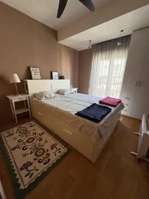 a bedroom with a bed and a window with a rug at Cozy apartment in the very city center in Podgorica