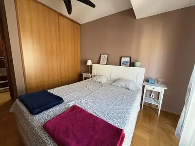 a bedroom with a large bed with purple blankets on it at Cozy apartment in the very city center in Podgorica