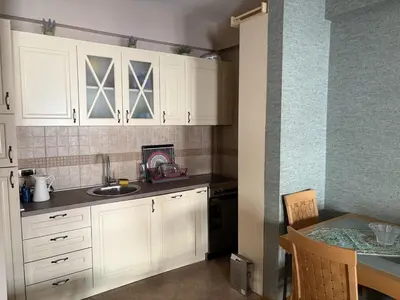 a kitchen with white cabinets and a sink and a table at Cozy apartment in the very city center in Podgorica