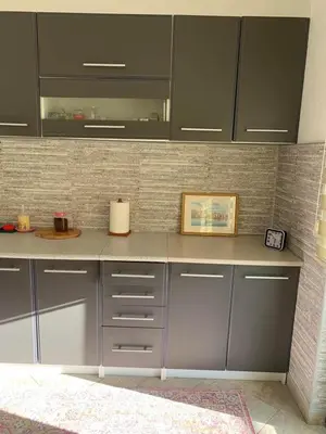 a kitchen with gray cabinets and a tile wall at Villa Andrea Lower Level in Kavač